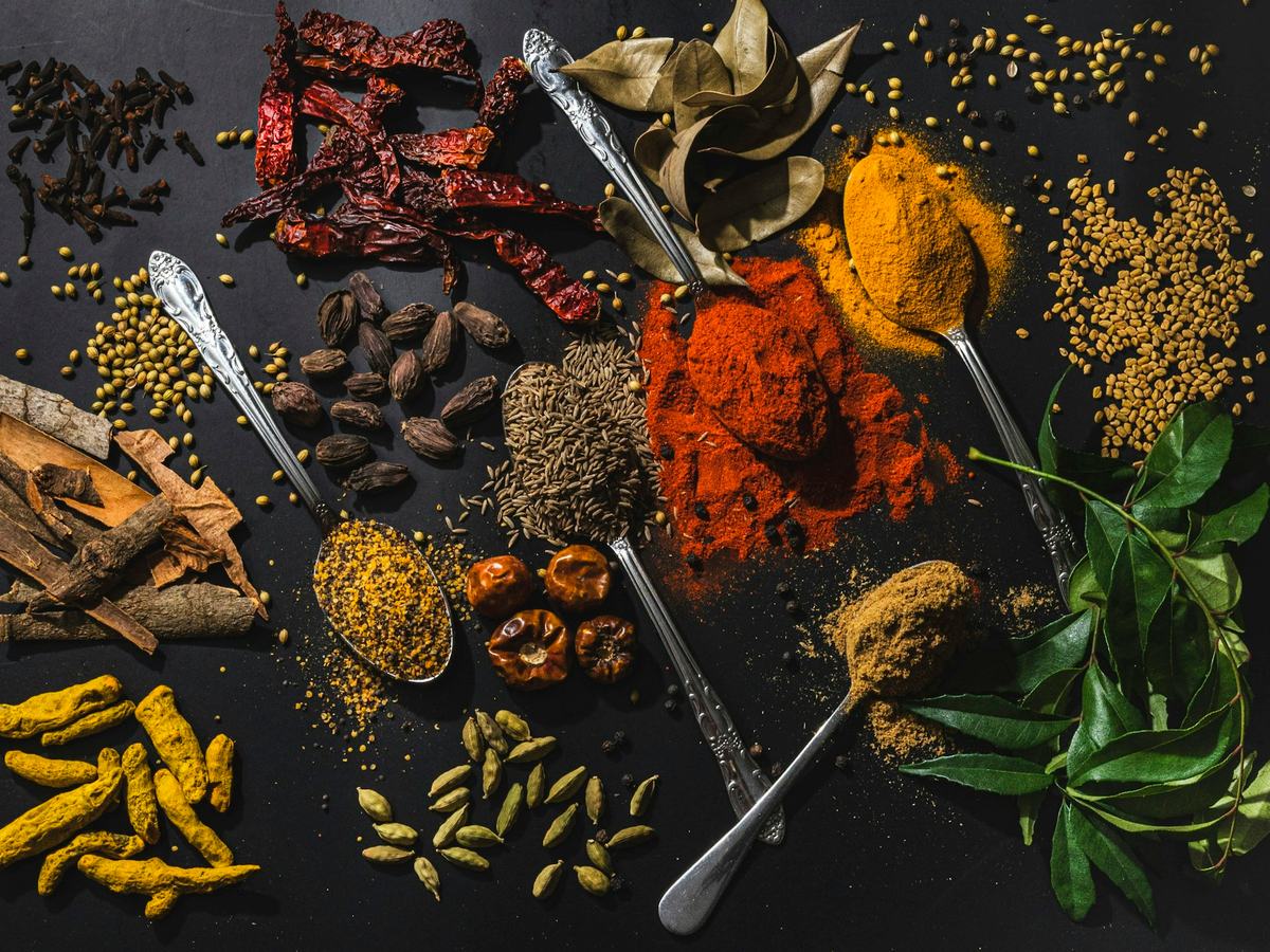 Whole and ground spices laid out with silver spoons